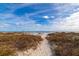 Sandy path leading to a tranquil beach with native landscaping and ocean views at 265 Minorca Beach Way # 902, New Smyrna Beach, FL 32169
