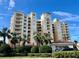 Luxurious condo building featuring multi-story balconies and lush landscaping against a beautiful blue sky at 265 Minorca Beach Way # 902, New Smyrna Beach, FL 32169