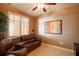 Living area showcasing a leather sofa, ceiling fan, and a window with decorative blinds at 265 Minorca Beach Way # 902, New Smyrna Beach, FL 32169