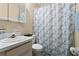 Well-lit bathroom featuring a vanity with sink, toilet, and a shower with seashell patterned curtain at 2901 N Halifax Ave # 215, Daytona Beach, FL 32118