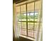 Bright window view overlooking the front yard, porch, and neighborhood, framed by sheer curtains at 2918 Mango Tree Dr, Edgewater, FL 32141