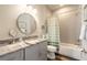 Well-lit bathroom with vanity, round mirror, and bathtub shower with a striped curtain at 3027 Portofino Blvd, New Smyrna Beach, FL 32168