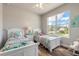 Bright bedroom featuring two twin beds, colorful bedding, and a large window with a view at 3027 Portofino Blvd, New Smyrna Beach, FL 32168