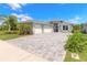 Inviting home featuring a wide driveway, three-car garage, and lush landscaping under a bright blue sky at 3027 Portofino Blvd, New Smyrna Beach, FL 32168