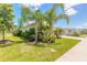 Landscaped yard featuring palm trees and lush green grass, enhancing the property's curb appeal at 3027 Portofino Blvd, New Smyrna Beach, FL 32168