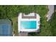 Overhead view of a pool surrounded by trees, lounge chairs, and tennis courts at 4403 Sea Mist Dr # 109, New Smyrna Beach, FL 32169