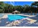 Outdoor pool area with lounge chairs, a covered gazebo, and lush green trees, creating a relaxing environment at 4403 Sea Mist Dr # 109, New Smyrna Beach, FL 32169