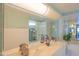 A bathroom featuring double sinks, a large mirror, and decorative wallpaper at 4555 S Atlantic Ave # 4405, Ponce Inlet, FL 32127