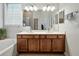 Bathroom featuring double sinks, vanity with brown cabinets, tub, framed mirror, and neutral walls at 461 Luna Bella Ln, New Smyrna Beach, FL 32168