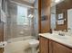 Neutral bathroom with a shower-tub, a window, and vanity with wood cabinets at 461 Luna Bella Ln, New Smyrna Beach, FL 32168