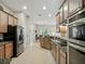 Kitchen with stainless steel appliances, wood cabinets and view into living room at 461 Luna Bella Ln, New Smyrna Beach, FL 32168
