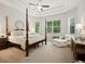 Main bedroom with four-poster bed, tray ceiling, fan and sitting area at 461 Luna Bella Ln, New Smyrna Beach, FL 32168