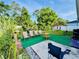 A relaxing backyard with a green lawn, mature trees, chairs, and an outdoor seating area at 520 Aeolian Dr, New Smyrna Beach, FL 32168