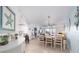 Bright open-concept dining room featuring modern chandelier, coastal decor, and access to outdoor balcony at 5300 S Atlantic Ave # 11302, New Smyrna Beach, FL 32169