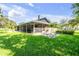 Expansive backyard with lush lawn, patio, screened-in porch, barbecue area, mature trees, and a serene outdoor setting at 544 Bottlebrush Ct, New Smyrna Beach, FL 32168