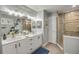 Bathroom with double sink vanity, tiled shower, and well-lit mirrors at 544 Bottlebrush Ct, New Smyrna Beach, FL 32168