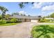 Brick home featuring a large driveway, a two-car garage, manicured lawn, and mature landscaping at 544 Bottlebrush Ct, New Smyrna Beach, FL 32168