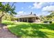 Spacious home exterior with a well-manicured lawn, covered patio, brick facade, and mature trees at 544 Bottlebrush Ct, New Smyrna Beach, FL 32168