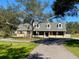 Charming brick home featuring dormer windows, mature trees, and a long driveway on a lush green lawn at 5832 Michelle Ln, Sanford, FL 32771