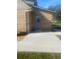 A brick house with a small concrete patio, brick wall, lawn, and a door leading to the backyard at 5832 Michelle Ln, Sanford, FL 32771