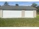 Exterior view of garage with two closed white garage doors, light siding and green lawn at 5832 Michelle Ln, Sanford, FL 32771