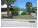 Exterior of a green home surrounded by mature trees and a chain link fence at 585 Washington St, New Smyrna Beach, FL 32168