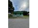 Front exterior of a compact green house with a small covered porch and adjacent, fenced yard at 585 Washington St, New Smyrna Beach, FL 32168
