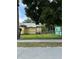 Exterior view of a yellow home with a metal roof and a chain link fence at 585 Washington St, New Smyrna Beach, FL 32168