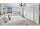 Bright bedroom with a ceiling fan, white bedding, and large closet with louvered doors at 6883 S Atlantic Ave, New Smyrna Beach, FL 32169