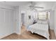 All-white bedroom featuring a ceiling fan, wood flooring and an adjoining bathroom at 6883 S Atlantic Ave, New Smyrna Beach, FL 32169