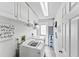 Bright laundry room with white cabinets, washer, dryer, and access to the exterior at 6883 S Atlantic Ave, New Smyrna Beach, FL 32169