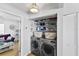 Laundry room with washer and dryer, storage shelves, and view into the living room at 6883 S Atlantic Ave, New Smyrna Beach, FL 32169