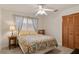 Cozy bedroom with floral bedding, a ceiling fan, a bedside table with a lamp, and a window at 6956 Turtlemound Rd, New Smyrna Beach, FL 32169