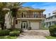 Two-story home with a balcony, garage, and a front yard featuring lush landscaping and mature palm trees at 6956 Turtlemound Rd, New Smyrna Beach, FL 32169