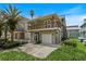 Two-story home featuring a balcony, a garage, and a well-manicured front yard with verdant landscaping at 6956 Turtlemound Rd, New Smyrna Beach, FL 32169