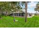 Backyard with manicured lawn, mature trees, and screened lanai at 757 Hunt Club Trl, Port Orange, FL 32127
