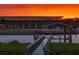 Scenic view of a waterfront property with a long pier and a building silhouetted against a vibrant sunset sky at 8 Richmond Dr, New Smyrna Beach, FL 32169
