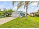 Inviting single-Gathering home featuring a lush front yard, palm tree, and an attached two-car garage at 805 Spruce St, New Smyrna Beach, FL 32168