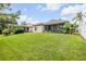 A spacious backyard featuring lush green lawn, mature landscaping, and screened lanai at 850 Wingate Trl, Port Orange, FL 32128