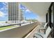 Condo balcony with seating offers ocean views, overlooking a sandy beach, palm trees and nearby buildings at 901 S Atlantic Ave # 202, Ormond Beach, FL 32176