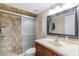 Bathroom featuring updated shower, vanity with bright lighting, and natural stone features at 1 Oceans West Blvd # 1B5, Daytona Beach, FL 32118