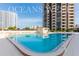 Refreshing pool area surrounded by modern buildings, lounge chairs, and a bright blue sky at 1 Oceans West Blvd # 1B5, Daytona Beach, FL 32118