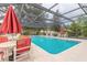 Enclosed outdoor swimming pool with seating, umbrellas, and green landscaping at 1237 Charter Oaks Cir, Daytona Beach, FL 32117