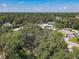 Overhead shot of a neighborhood featuring lush, mature trees and several single-Gathering homes under a blue sky at 1421 Pine Tree Dr, Edgewater, FL 32132