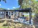 Lush backyard with a patio, modern pergola with outdoor seating, and grill at 1421 Pine Tree Dr, Edgewater, FL 32132
