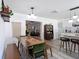 Open dining area with wooden table, green chairs, bench, flowing into kitchen and living room at 1421 Pine Tree Dr, Edgewater, FL 32132