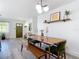 Dining area with wooden table, bench seating, modern light fixture, and view of the front door at 1421 Pine Tree Dr, Edgewater, FL 32132