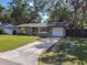 Charming home with a well-manicured lawn and a paved driveway leading to an attached garage at 1421 Pine Tree Dr, Edgewater, FL 32132