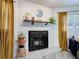 Brick fireplace with black insert, mantle shelf with decor, flanked by windows with mustard curtains at 1421 Pine Tree Dr, Edgewater, FL 32132
