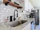 Kitchen sink detail with stainless steel faucet, granite countertops, subway tiles, and a wooden shelf at 1421 Pine Tree Dr, Edgewater, FL 32132